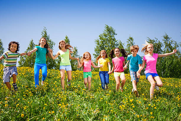 istock Playful children run, hold hands in green field 504056101