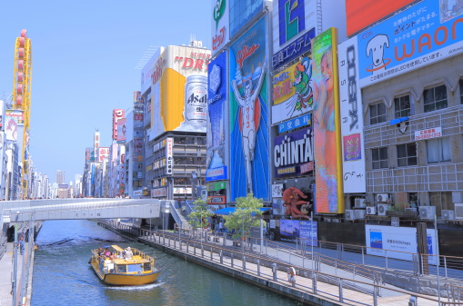 Osaka, Japan - 19 June, 2014: Tourists sightsee Dotonbori entertainment district by boat in Osaka Japan.