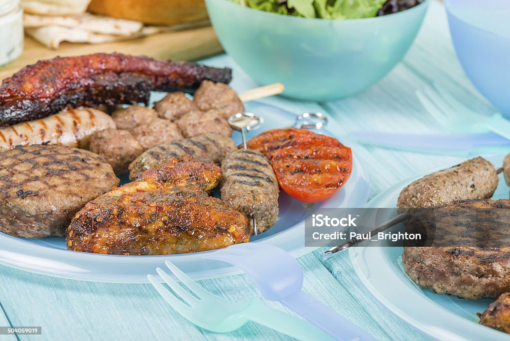 BBQ Assorted barbequed meat and bread on a blue background. Served with coleslaw, yoghurt and cucumber dip and chili sauce. Outdoors summer meal! American Culture Stock Photo