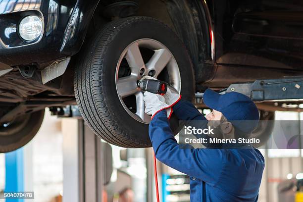 Portrait Of A Mechanic Replacing Wheel Stock Photo - Download Image Now - Tire - Vehicle Part, Repairing, Auto Repair Shop