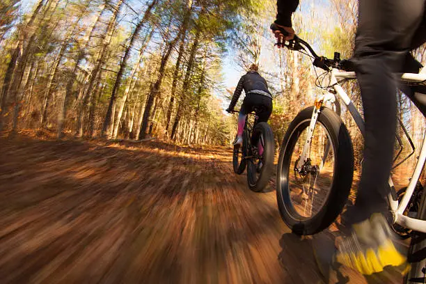 Couple riding fatbikes on trails in the fall
