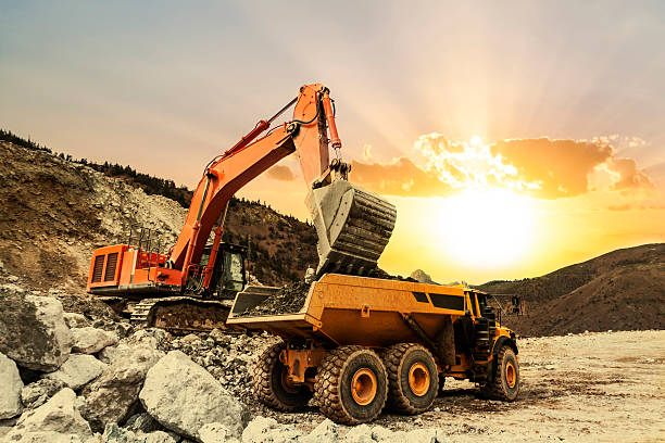 Excavator loading dumper truck on mining site Excavator loading dumper truck on mining site at sunset. agricultural machinery photos stock pictures, royalty-free photos & images