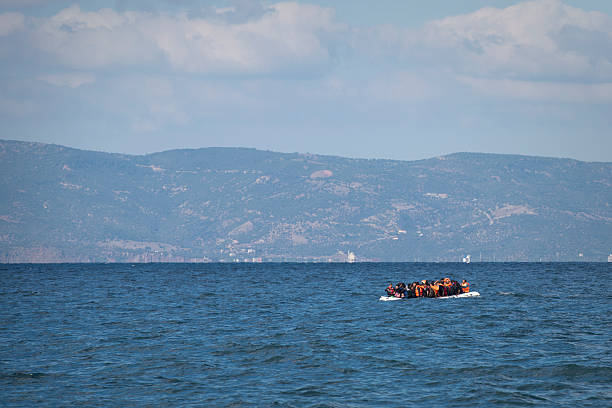 Lesbos, Greece - October 25, 2015: An inflatable boat filled with migrants approaches the north coast of the Greek island of Lesbos. Turkey is visible in the background.