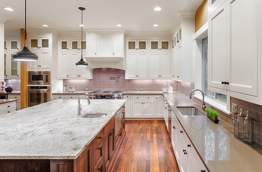 Large kitchen interior with hardwood floors, two sinks, pendant lights, and wrap around cabinets