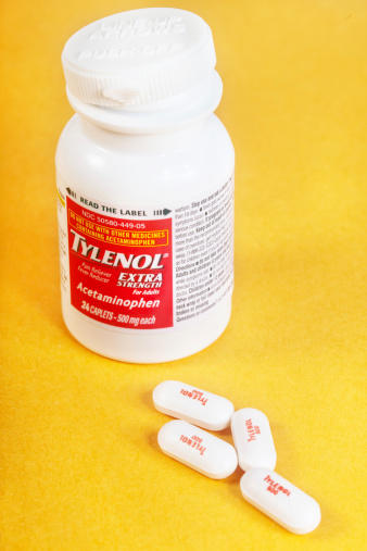 Fair Oaks, California, USA - June 27, 2014: Open bottle of Tylenol Extra Strength pain reliever and fever reducer medicine with four 500 mg tablets laying outside. Tylenol is popular brand of Acetaminophen medication produced by McNEIL-PPC, Inc.