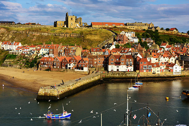Whitby, England - August 11, 2015: Whitby  church, town,  abbey, harbour wall and beach in North Yorkshire, England. Picturesque fishing town with distant people.