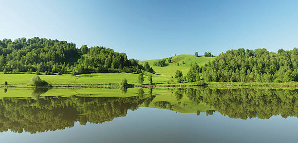 Beautiful summer panorama with green hills reflected in the calm water