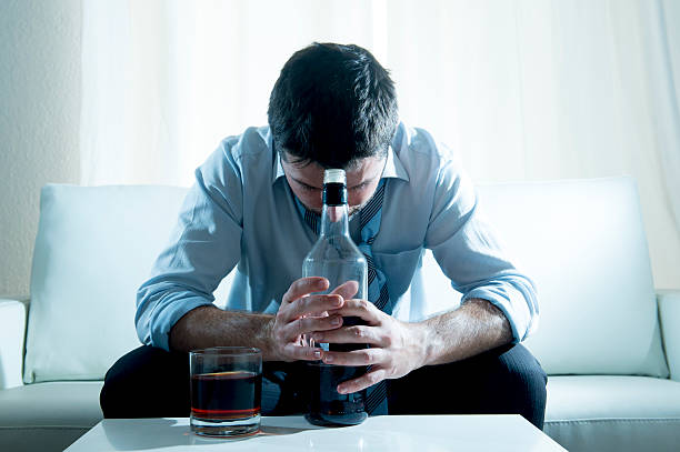 Businessman wearing blue shirt drunk at desk on white background stock photo