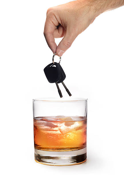 мужчина рука держа ключи от автомобиля на стакан виски - designated driver стоковые фото и изображения