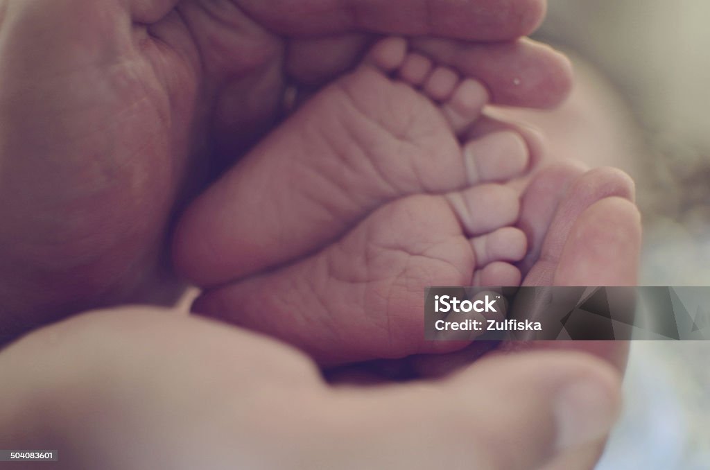 baby feet Daddy's hand holding baby's feet Premature Stock Photo