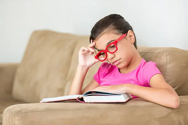 Young girl reading bored, with glasses
