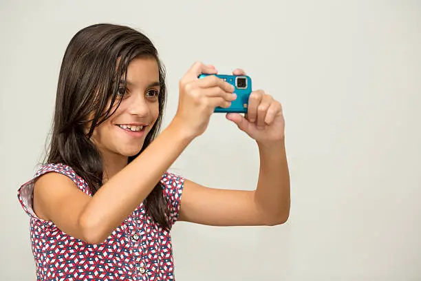 Young girl taking a photo, studio