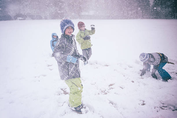 A group of children have a snowball fight in a storm at school