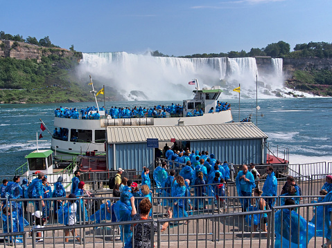 Niagara Falls, Canada - August 21, 2013:  Voyagers wearing blue raincoats board the Maid of the Mist tour boat to get up close to the falls.