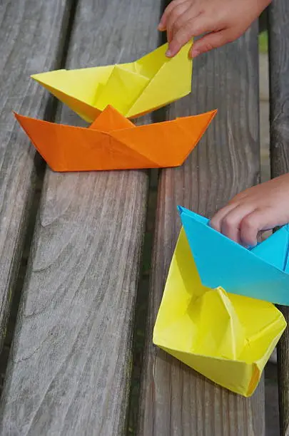 a child is folding a paper ship