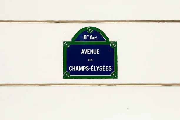 Avenue des champs-elysees street sign on beige wall.
