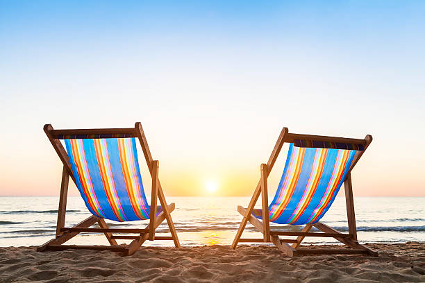 due sedie a sdraio sulla spiaggia di sabbia al tramonto - outdoor chair foto e immagini stock