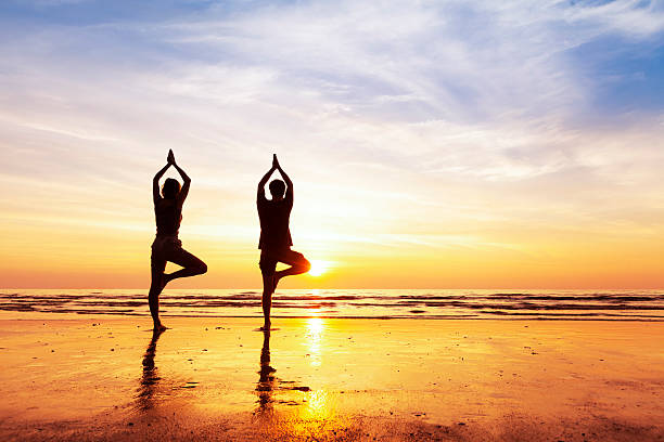 zwei menschen yoga baum position am strand, sonnenuntergang - travel caribbean caribbean sea sea stock-fotos und bilder