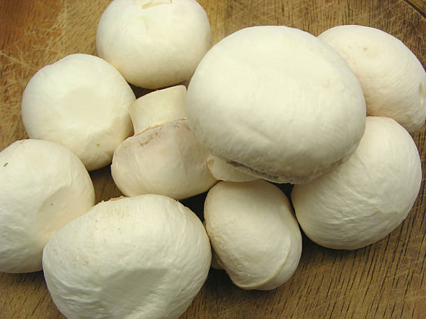 istock White  mushrooms on a brown wooden plate 504103987