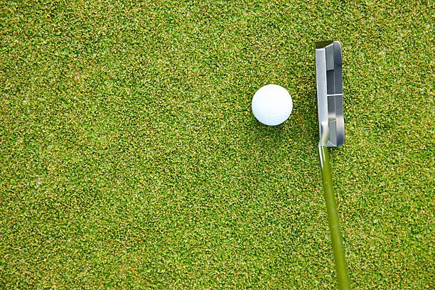 Close up of a putter and golf ball on a manicured green