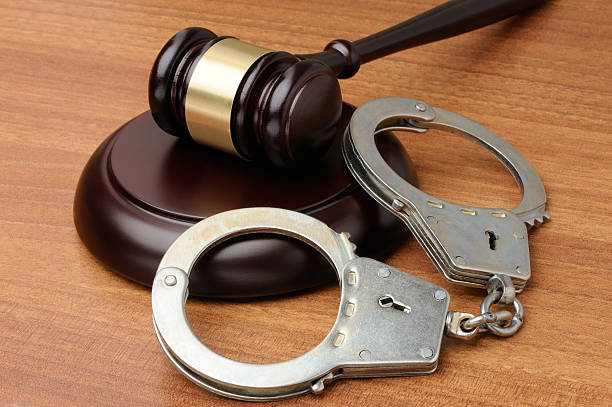 Handcuffs with gavel on a wood background stock photo