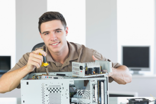 Handsome cheerful computer engineer repairing open computer in bright office