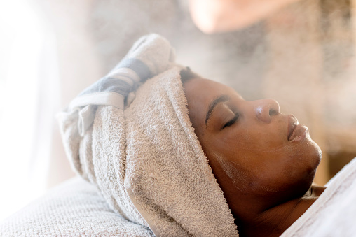 Adult African woman relaxing & enjoying a facial treatment at a beauty salon.