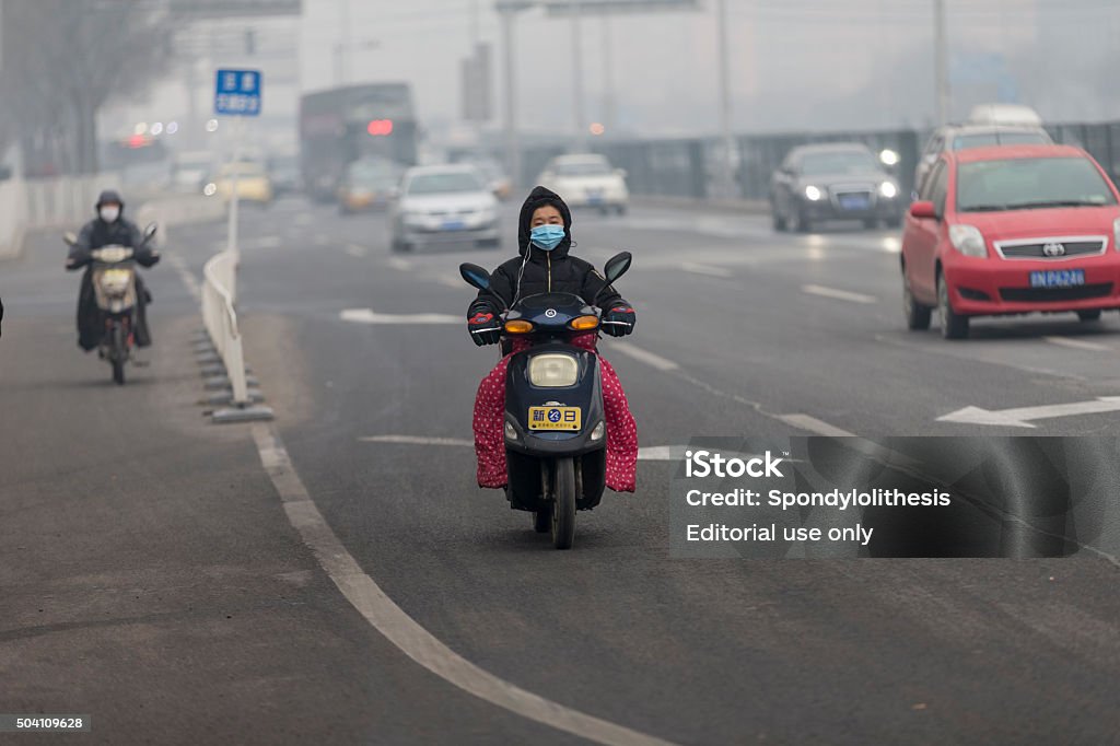 Electric Bike in Beijing Beijing, China - December 7, 2015: Two men driving  electric bikes with  gloves in the winter time. Obvious smog on the background. Air Pollution Stock Photo