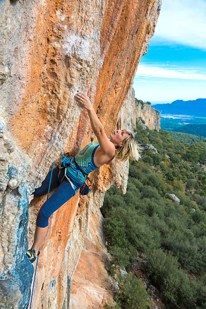 istock Blond Female Climber ascending Vertical Orange Rock 504112312
