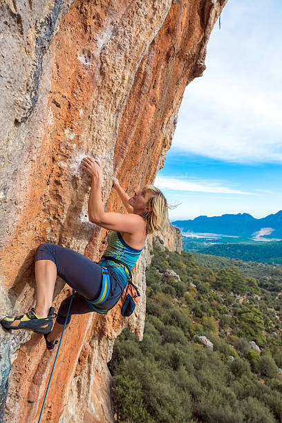 istock Blond Female Climber ascending Vertical Orange Rock 504112450