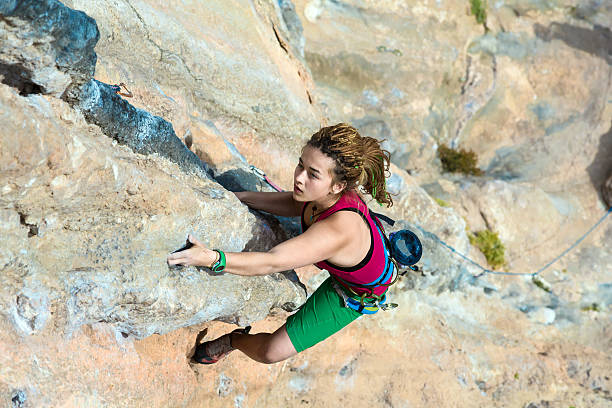 vue du haut du rocher suspendu un jeune grimpeur paroi rocheuse - climbing mountain climbing rock climbing women photos et images de collection