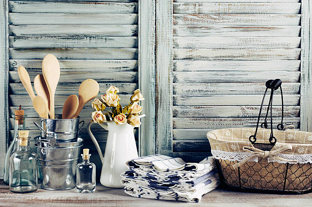 Rustic kitchen still life Rustic kitchen still life: wire basket, galvanized buckets with wooden spoons, jug with roses bunch, towels stack and glass bottles against vintage wooden shutters. Filtered toned image. farmhouse stock pictures, royalty-free photos & images