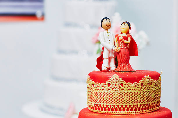 Beautiful red and yellow wedding cake in Indian style Beautiful red and yellow wedding cake in Indian style with bride and groom figurines on top wedding cake close up macro stock pictures, royalty-free photos & images