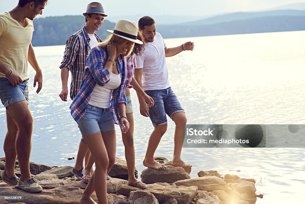 Summertime joy Cheerful young friends walking along stone coastline Friendship Stock Photo