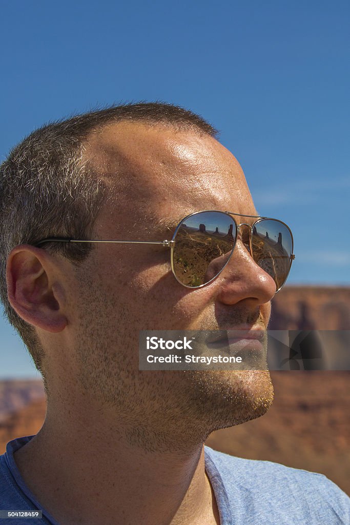 Reflective moments Young man with reflective sunglasses is overwhelmed by the beauty of Monument Valley. Adult Stock Photo