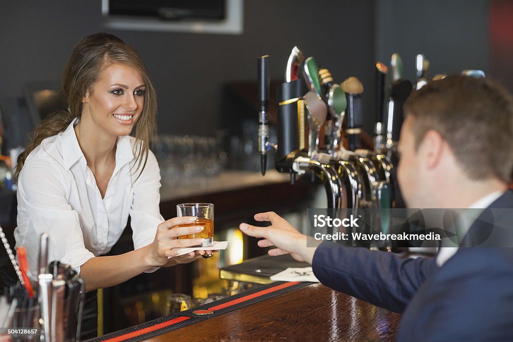 Beautiful waitress serving handsome businessman Beautiful waitress serving handsome businessman in a classy bar Bartender Stock Photo