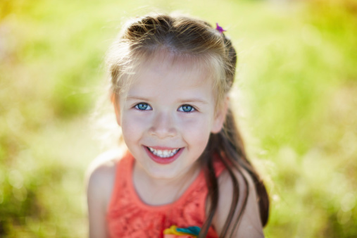 Portrait of a cheerful little girl having fun in the nature. Shallow depth of field