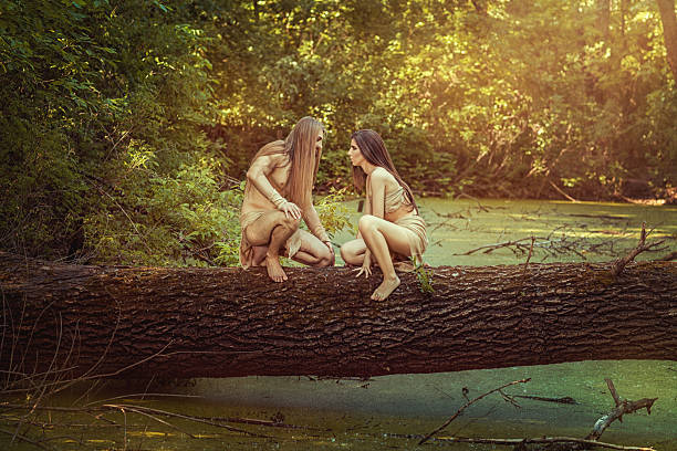 On a tree in the forest sitting wild man and woman and looking at each other.