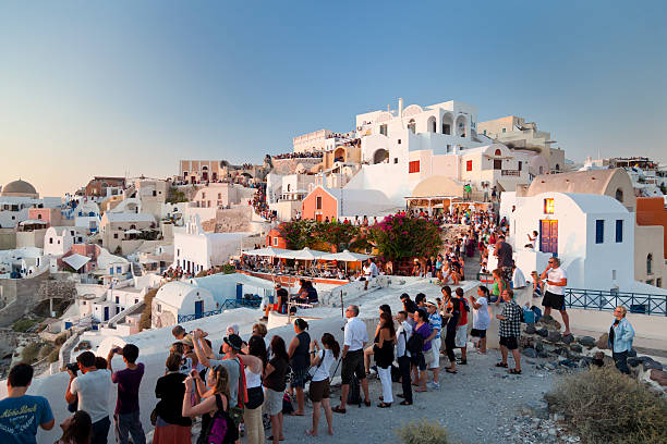 Tourists In Oía, Santorini Oia, Greece - September 5, 2011: Lots of tourists watching sunset from the famous evening meeting point on the tip of Oia. santorin stock pictures, royalty-free photos & images