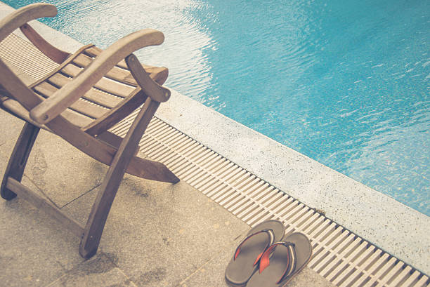 Wooden chair and slippers beside swimming pool stock photo