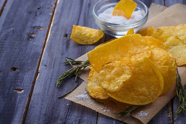 istock Potato chips with rosemary on wooden background 504182488