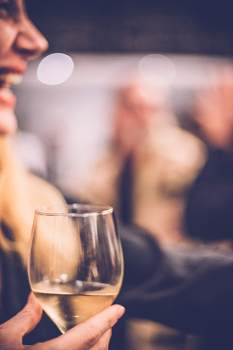 Young woman holding a glass of white wine, part of the body, selective focus