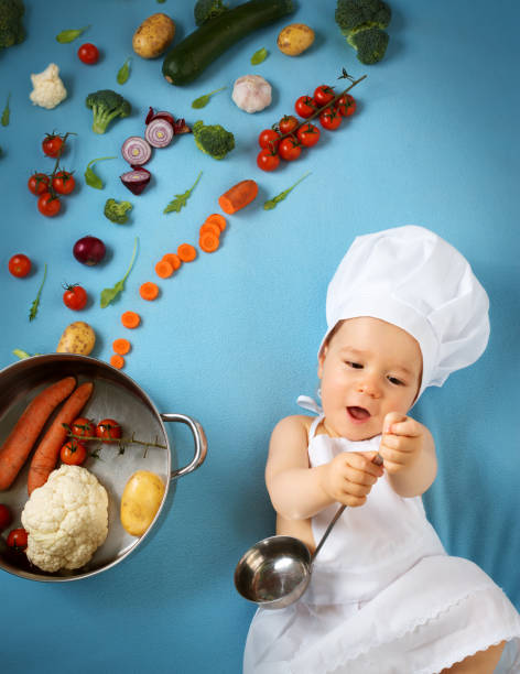 istock Baby boy in chef hat with cooking pan and vegetables 504187018