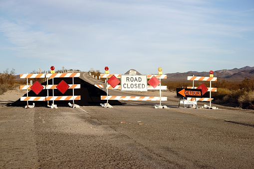 A road barrier with warning lights and a tar pile on Route 66.