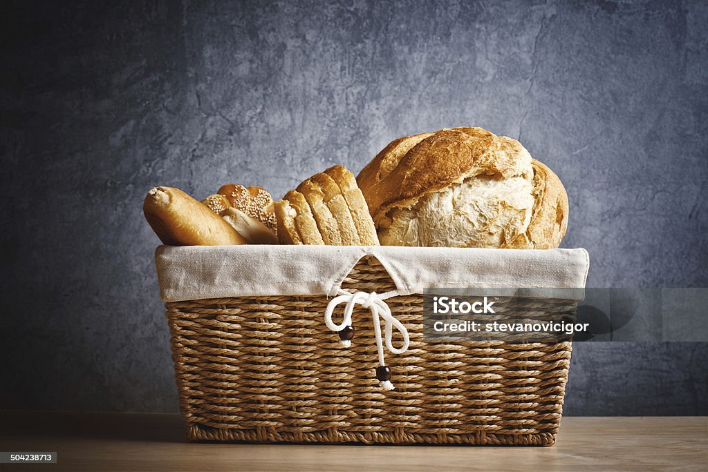 Delicious bread and rolls in wicker basket Delicious bread and rolls in wicker basket on kitchen table with copy space Baked Pastry Item Stock Photo