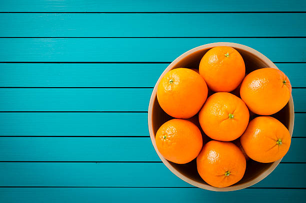 Oranges in bowl on wooden table stock photo