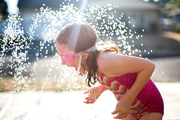 istock Young girls plays outside in sprinkler 504241348