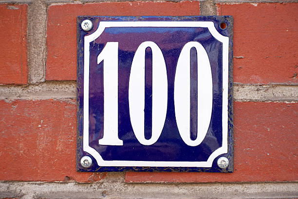 istock Blue house number plate Nr. 100 on brick wall 504241653
