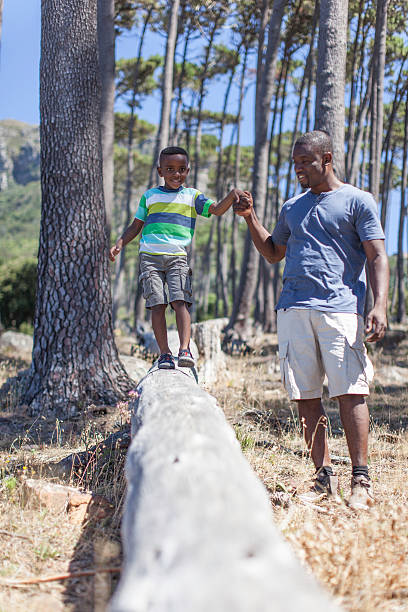 istock African father helping is son balance on a log 504241885