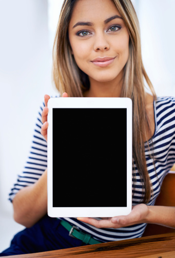 A portrait of a beautiful young woman showing a tablet with a blank screen
